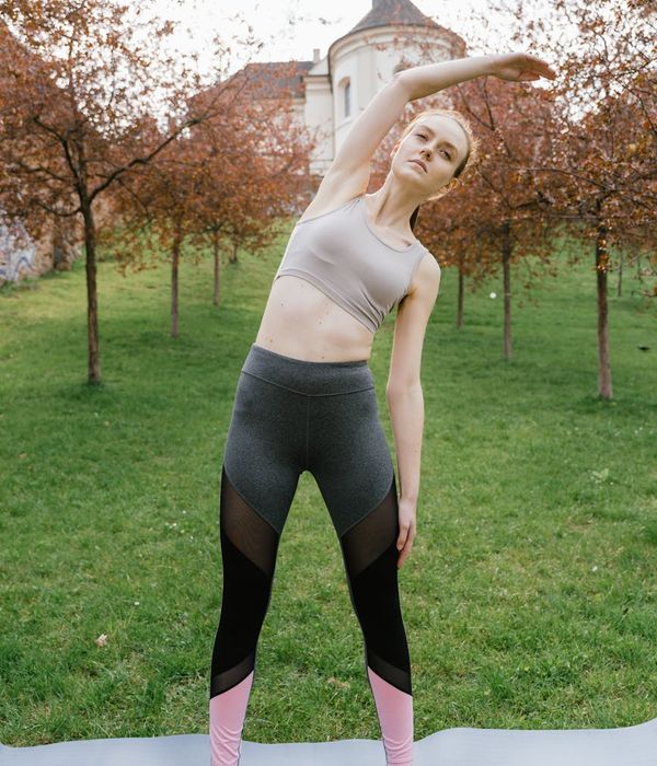Woman in a stable yoga pose on an olive green geometric background.